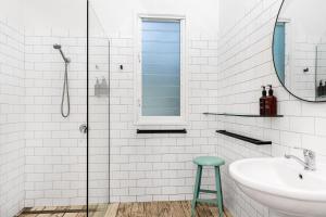a bathroom with a sink and a mirror and a stool at Cove Studios in Byron Bay