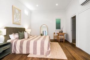 a white bedroom with a bed and a table at Cove Studios in Byron Bay