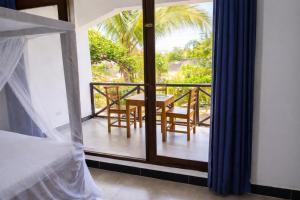 a bedroom with a balcony with a table and chairs at Majani Breeze Zanzibar in Nungwi