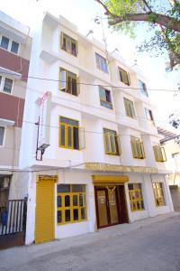 a white building with yellow doors on a street at Aruppukottai Nadar Lodge in Chennai