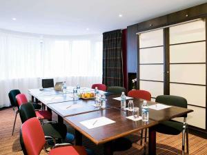 a conference room with a long table and red chairs at Hotel Mercure Rennes Cesson in Cesson-Sévigné