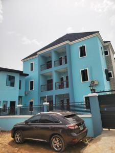 a black car parked in front of a blue building at Vingoze Apartments in Fatade