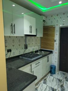 a kitchen with white cabinets and a green light at Vingoze Apartments in Fatade
