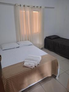 a bedroom with a bed with towels on it at Casa ampla e confortável em Cruz das Almas in Cruz das Almas