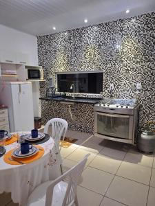 a kitchen with a stove and a table with chairs at Casa ampla e confortável em Cruz das Almas in Cruz das Almas