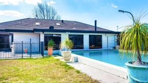 a house with a swimming pool and two palm trees at Ruthmor Villas in Toowoomba