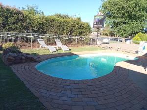 a swimming pool with two chairs and a sign at Memphis Motor Inn- UNDER NEW MANAGEMENT in Parkes