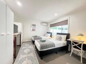 a bedroom with two beds and a desk and a window at North Ryde Guesthouse in Sydney