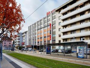 ein Gebäude an einer Straße, vor dem Autos parken in der Unterkunft ibis Annemasse-Genève in Ambilly