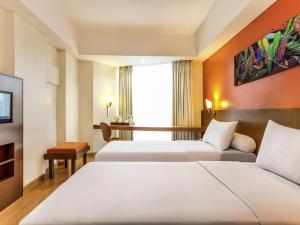 a hotel room with two beds and a table at ibis Semarang Simpang Lima in Semarang +31 photos