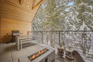 a room with a fireplace on a balcony with snow covered trees at Baernhaus in Government Camp