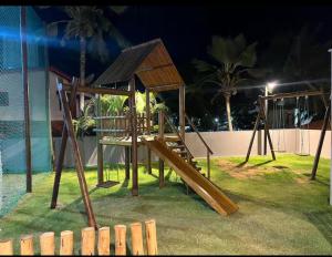a wooden playground with a slide on the grass at Beira mar Flat Deluxe Nomar Carneiros Ecoliving Réveillon in Tamandaré