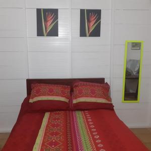a bed with two red pillows in a room at bungallow T2 Vernou in Petit-Bourg
