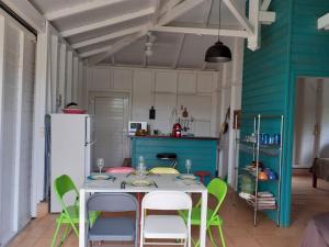 a kitchen with a table with chairs and a refrigerator at bungallow T2 Vernou in Petit-Bourg