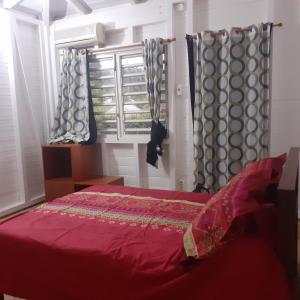 a bedroom with a red bed and a window at bungallow T2 Vernou in Petit-Bourg