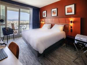 a hotel room with a large bed and a balcony at Mercure Thalasso & Spa Port Fréjus in Fréjus