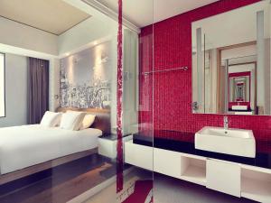 a bedroom with a bed and a sink and a mirror at Mercure Jakarta Simatupang in Jakarta