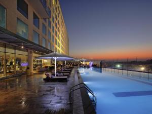 a building with a swimming pool in front of a building at Novotel Pune Viman Nagar Road in Pune
