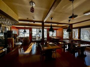 a large room with tables and chairs and windows at Tesoro Okushiga in Yamanouchi