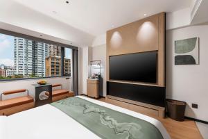a bedroom with a large bed and a flat screen tv at KSpace KaiShi hotel in Guangzhou