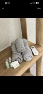 a pile of towels and a remote control on a shelf at Suíte próximo a BR! in São José