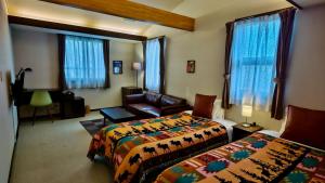 a hotel room with two beds and a couch at Tesoro Okushiga in Yamanouchi