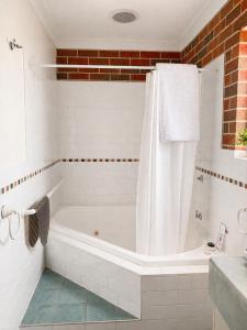 a white bathroom with a tub and a sink at Poachers Paradise in Rutherglen