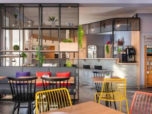 a restaurant with tables and yellow chairs in a room at ibis Kassel Melsungen in Melsungen