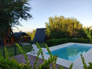 a swimming pool in a yard with a chair next to it at Cabañas Don Luis in Valle Hermoso