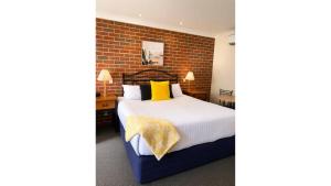 a bedroom with a bed and a brick wall at Poachers Paradise in Rutherglen