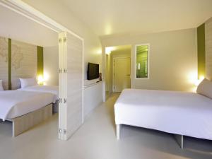 a bedroom with two beds and a television in it at ibis Styles Krabi Ao Nang in Ao Nang Beach
