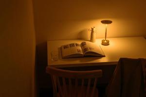 a book on a table with a lamp and a glass at メーイン北 in Tokyo