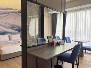 a room with a desk with chairs and a bed at Swiss-Belexpress Jemursari in Surabaya
