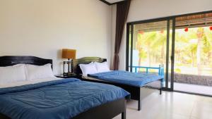 a bedroom with two beds and a sliding glass door at ZEN Resort - Villa beach- Garden in Xóm Tram