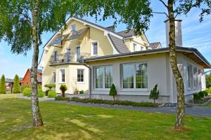 a large yellow house with trees in the yard at Villa Antoja in Grzybowo