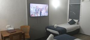 a hotel room with a bed and a tv on the wall at Memphis Motor Inn- UNDER NEW MANAGEMENT in Parkes
