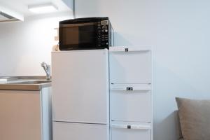 a microwave on top of a refrigerator in a kitchen at Park building Tenmonkan 1 in Kagoshima