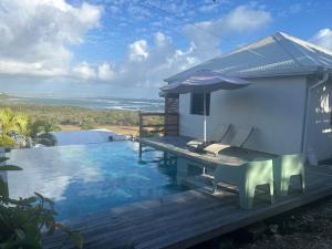 a pool with a table and chairs and an umbrella at Sukha Lodge in Le Moule