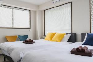 two beds in a room with chairs and windows at メーイン北 in Tokyo
