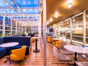 a restaurant with tables and chairs and windows at ibis Bogota Museo in Bogotá