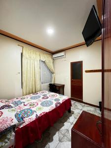 a bedroom with a bed and a flat screen tv at Hostal Amazónico Bello Amanecer in Nueva Loja