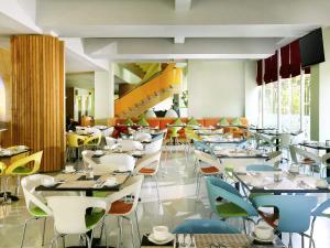 a restaurant with tables and chairs and a staircase at ibis Styles Yogyakarta in Yogyakarta