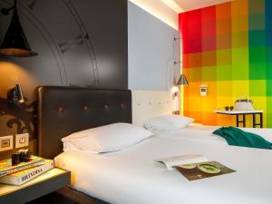 a bedroom with a white bed with a colorful wall at ibis Styles London Southwark - near Borough Market in London +108 photos