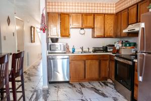 a kitchen with wooden cabinets and a stainless steel dishwasher at The Huntsville Nest - 2BR Near SHSU - Pool - WiFi - Free Parking in Huntsville