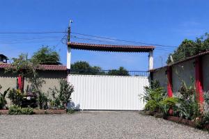 a white fence with a gate in a driveway at Hostal Amazónico Bello Amanecer in Nueva Loja