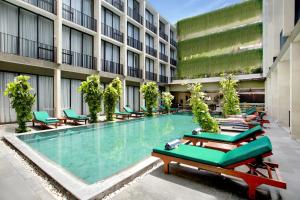 a large swimming pool in a building with lounge chairs at Hotel Terrace at Kuta in Legian