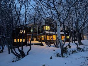 a house in the snow with trees in front of it at Tesoro Okushiga in Yamanouchi