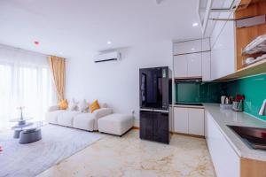 a living room with a white couch and a kitchen at Cannes Ben Tre Hotel in Ben Tre