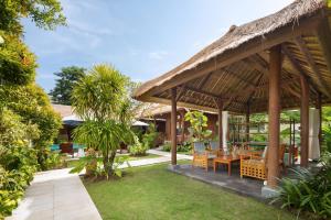 a pavilion with a table and chairs in a garden at Gecko Villa & Bungalows in Nusa Lembongan