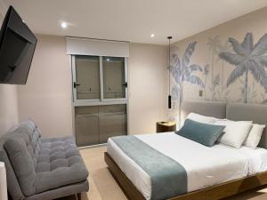 a bedroom with a bed and a chair and a television at El Zócalo Hotel Boutique in Filandia
